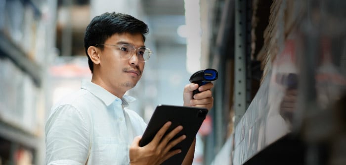 working in a warehouse scanning boxes with a handheld barcode scanner